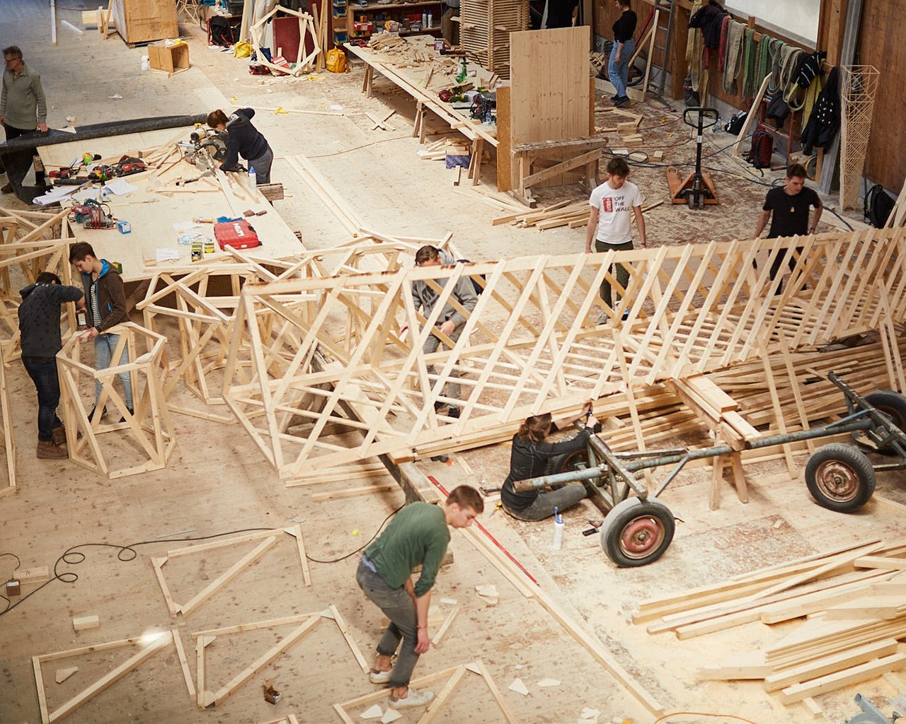Studierende bauen in einer Schreinerei einen Turm aus Holz