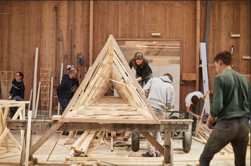Studierende bauen einen Turm aus Holz in einer Werkstatt
