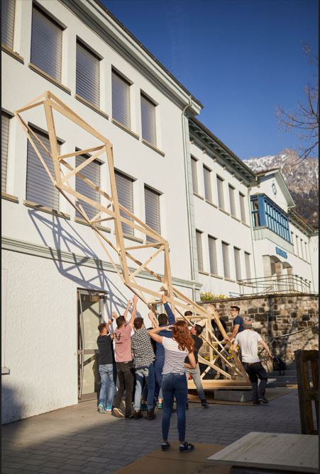Studierende richten gemeinsam einen Holzturm auf dem Rathauspaltz in Schaan auf