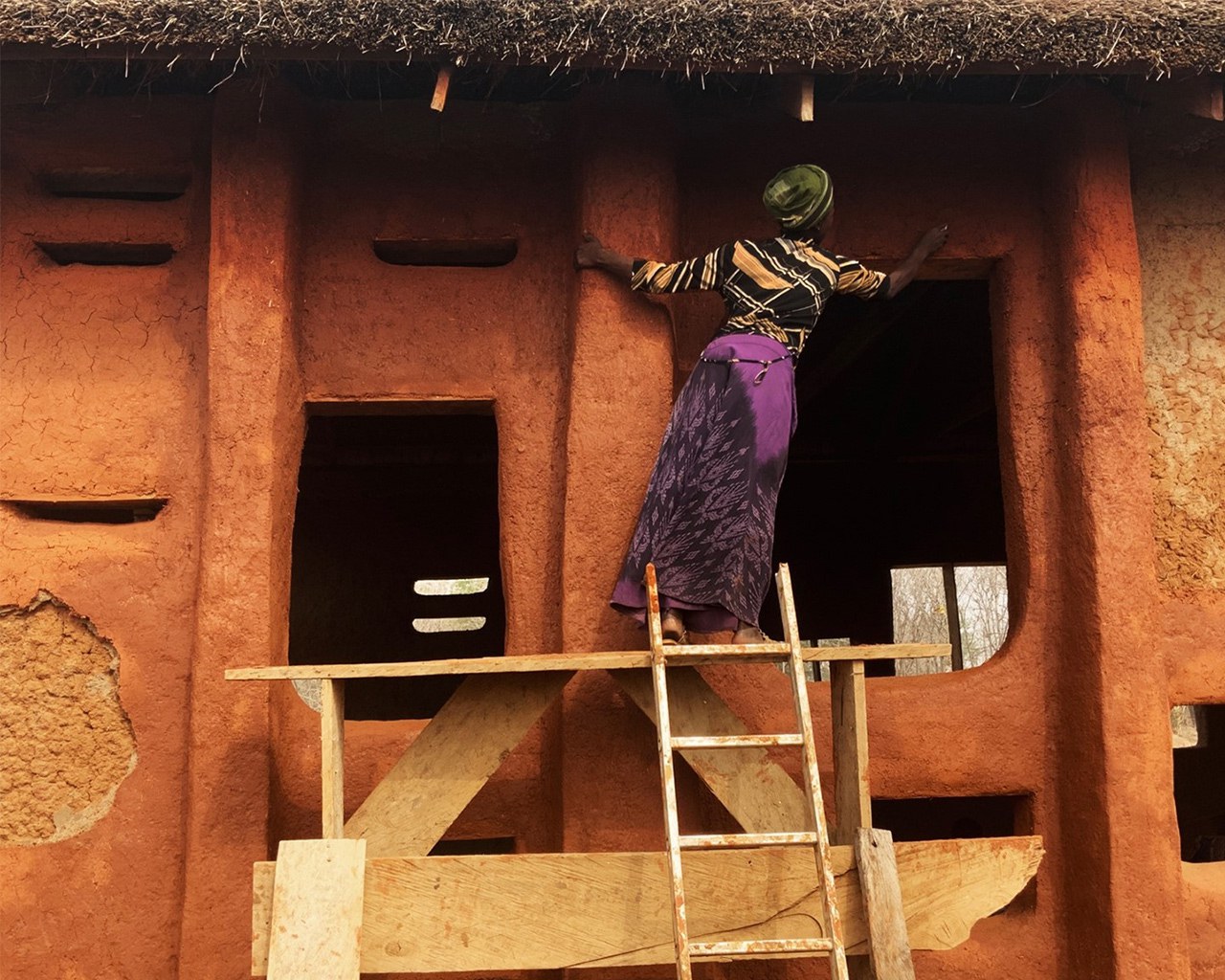Frau in Ghana baut ein Gebäude aus Lehm