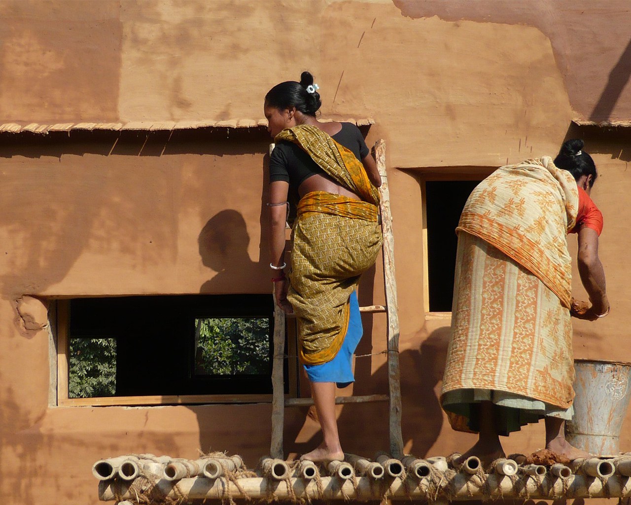 Frau in Bangladesh baut ein Gebäude aus Lehm