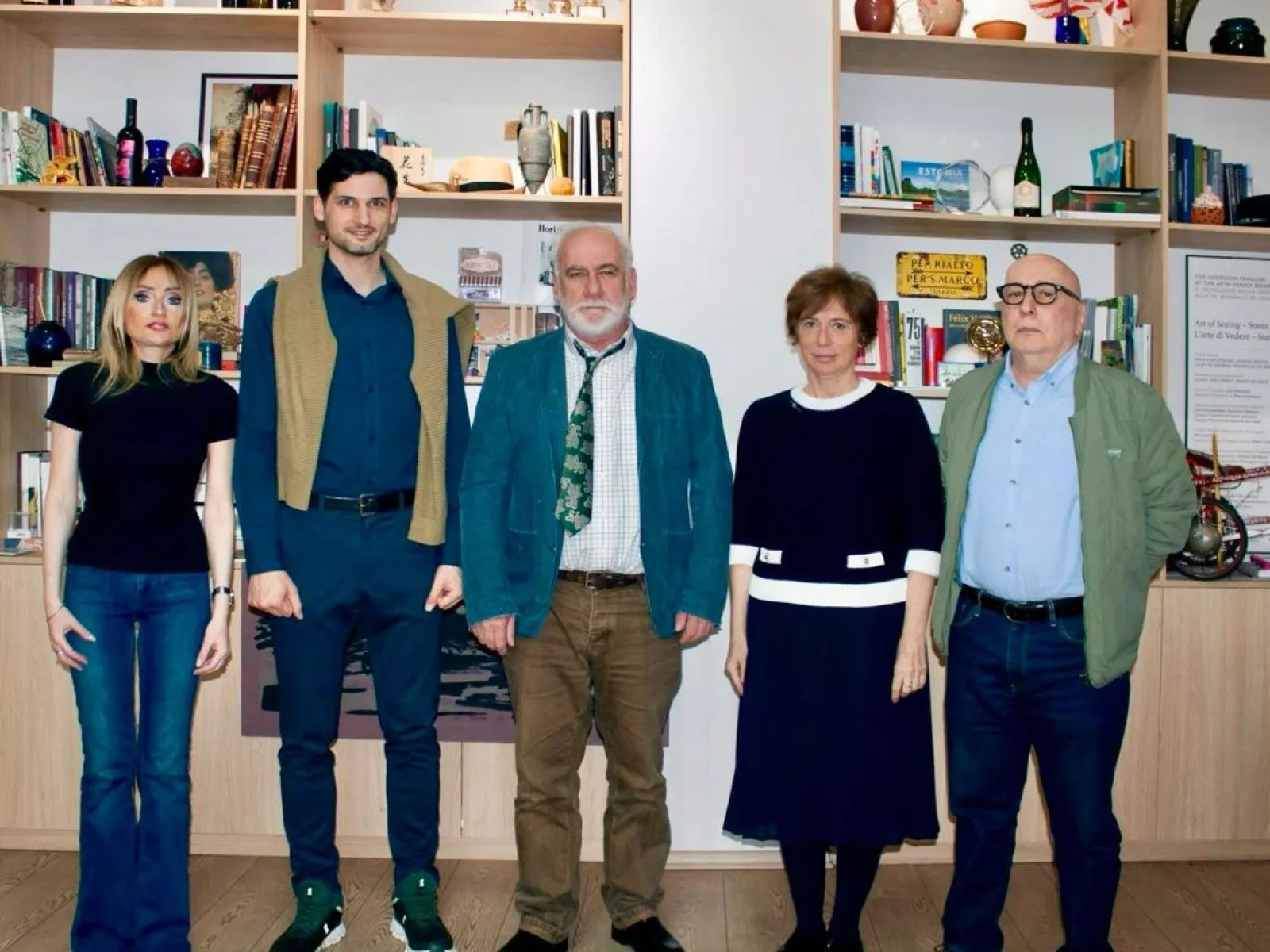 Gruppe von fünf Personen stehen vor einem Bücherregal.