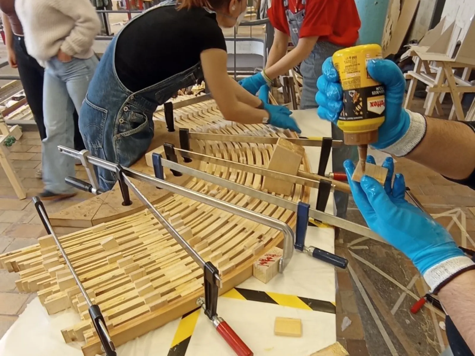 Ein Holzmodell eines Möbelstücks wird von Studierenden zusammengebaut.