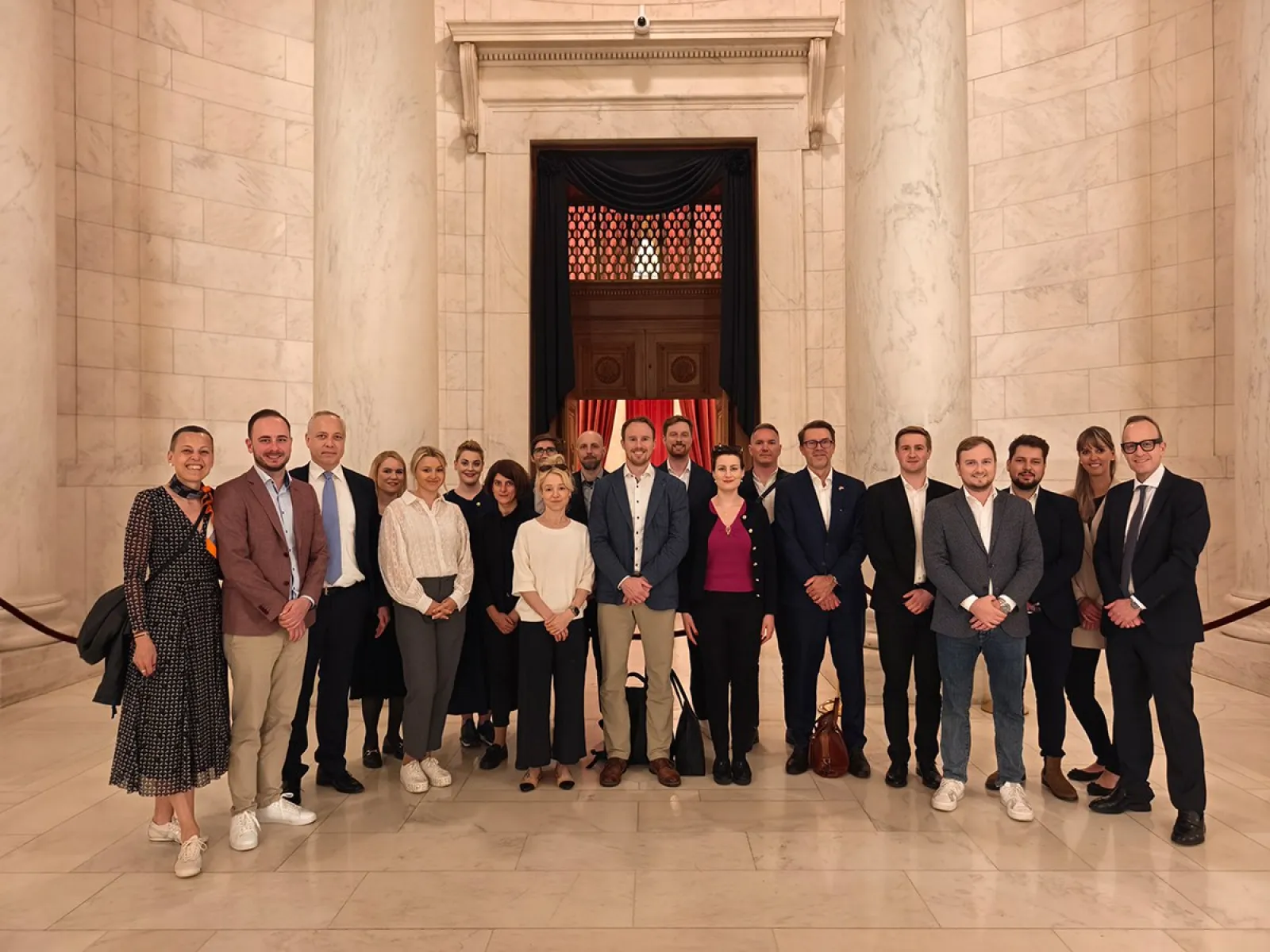 Eine Gruppe von Studierenden und Dozenten steht in einem eleganten, marmorgekleideten Innenraum. Sie posieren für ein Gruppenfoto während einer Studienreise in die USA, organisiert von der Universität Liechtenstein.