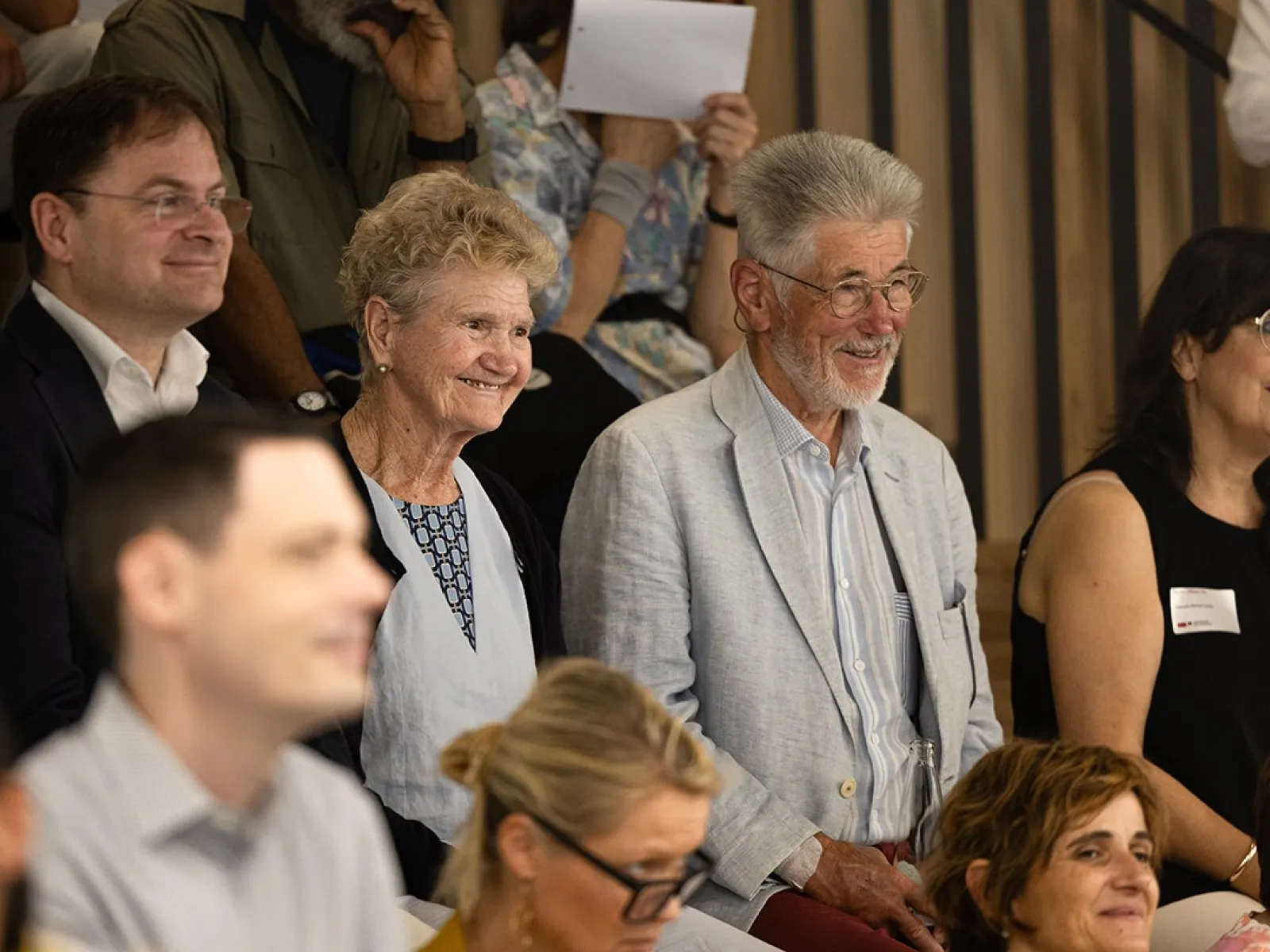 Eine Gruppe von Menschen sitzt lächelnd in einem Auditorium während des Tags der offenen Tür an der Universität Liechtenstein.