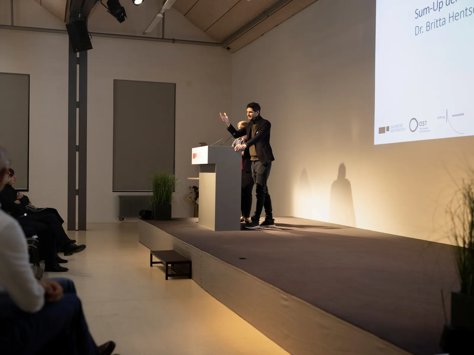 Eine vortragende Person auf einer Bühne 