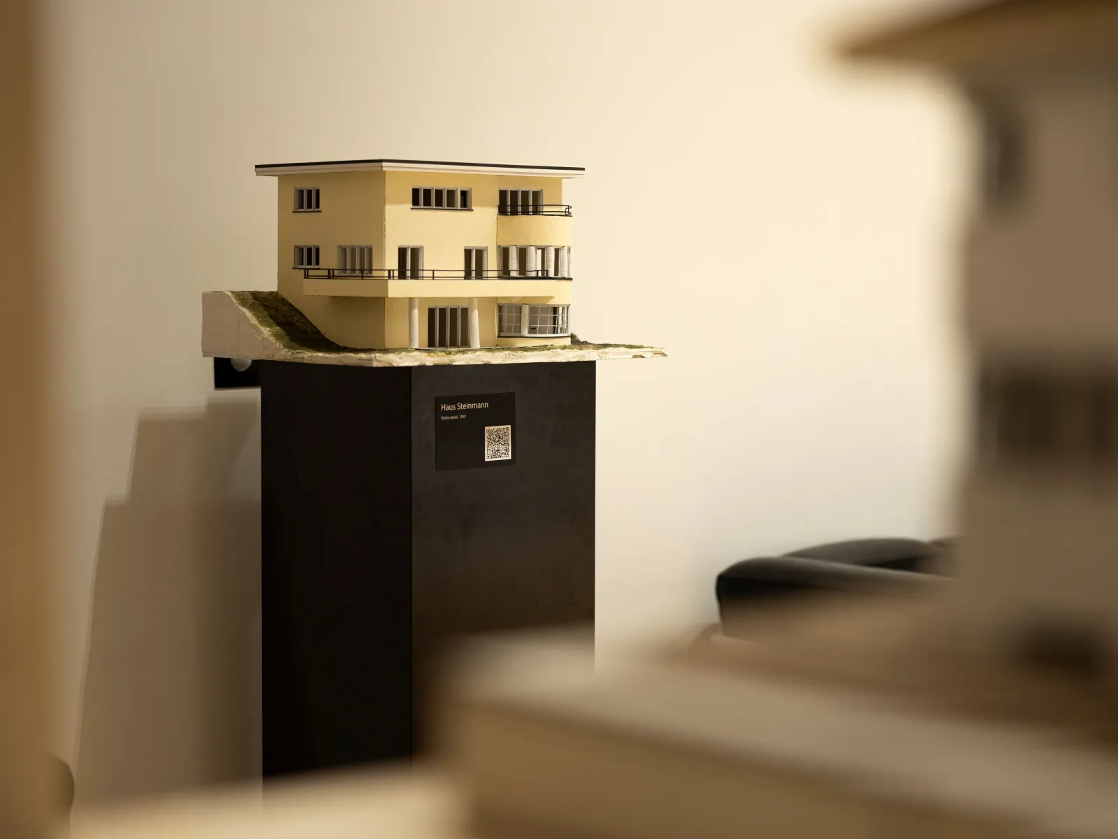 Ein beiges Architekturmodell auf einem schwarzen Ausstellungsbock
