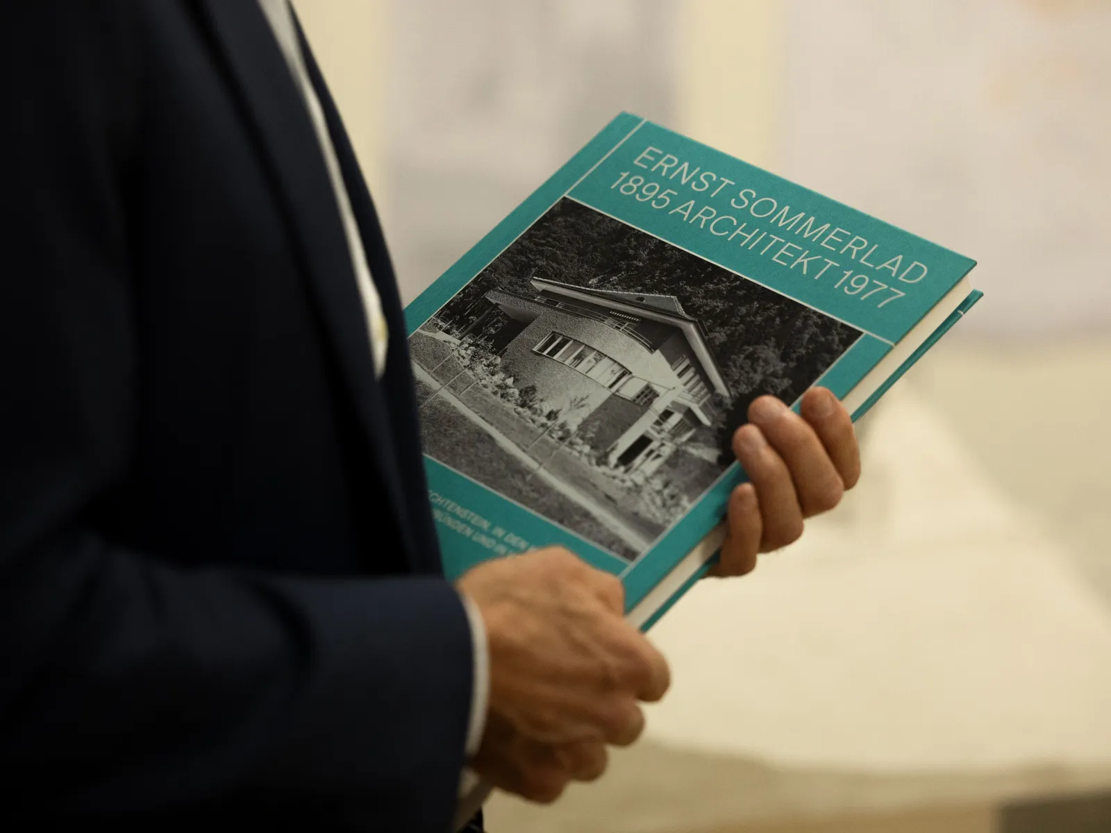 Eine Person hält ein blaues Buch mit dem Titel "Ernst Sommerlad"