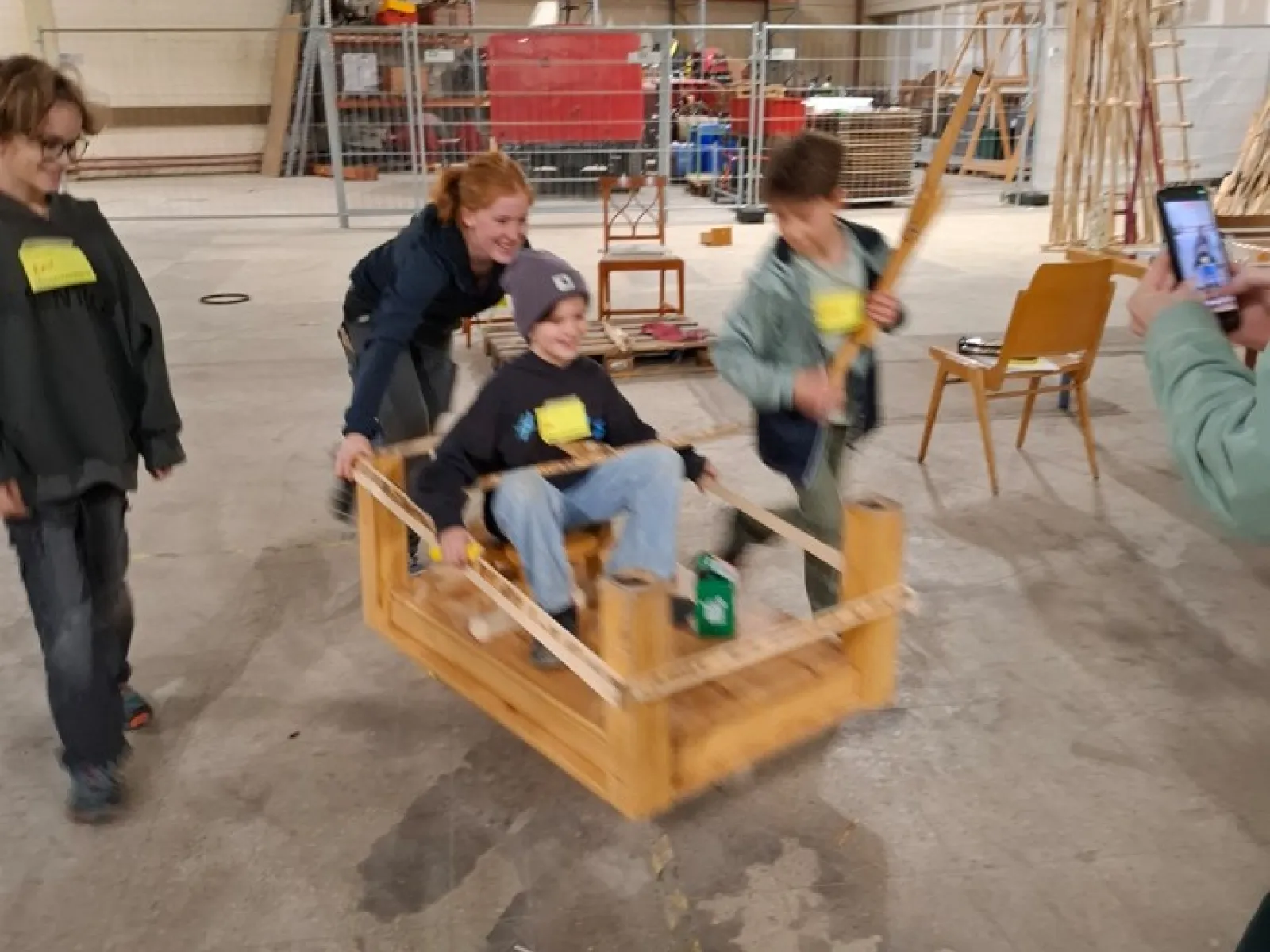 Mehrere Kinder schieben eine rollende Holzkiste