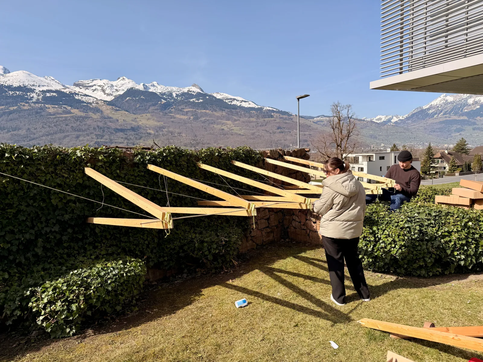 Drei junge Menschen bauen eine Konstruktion aus Holz 