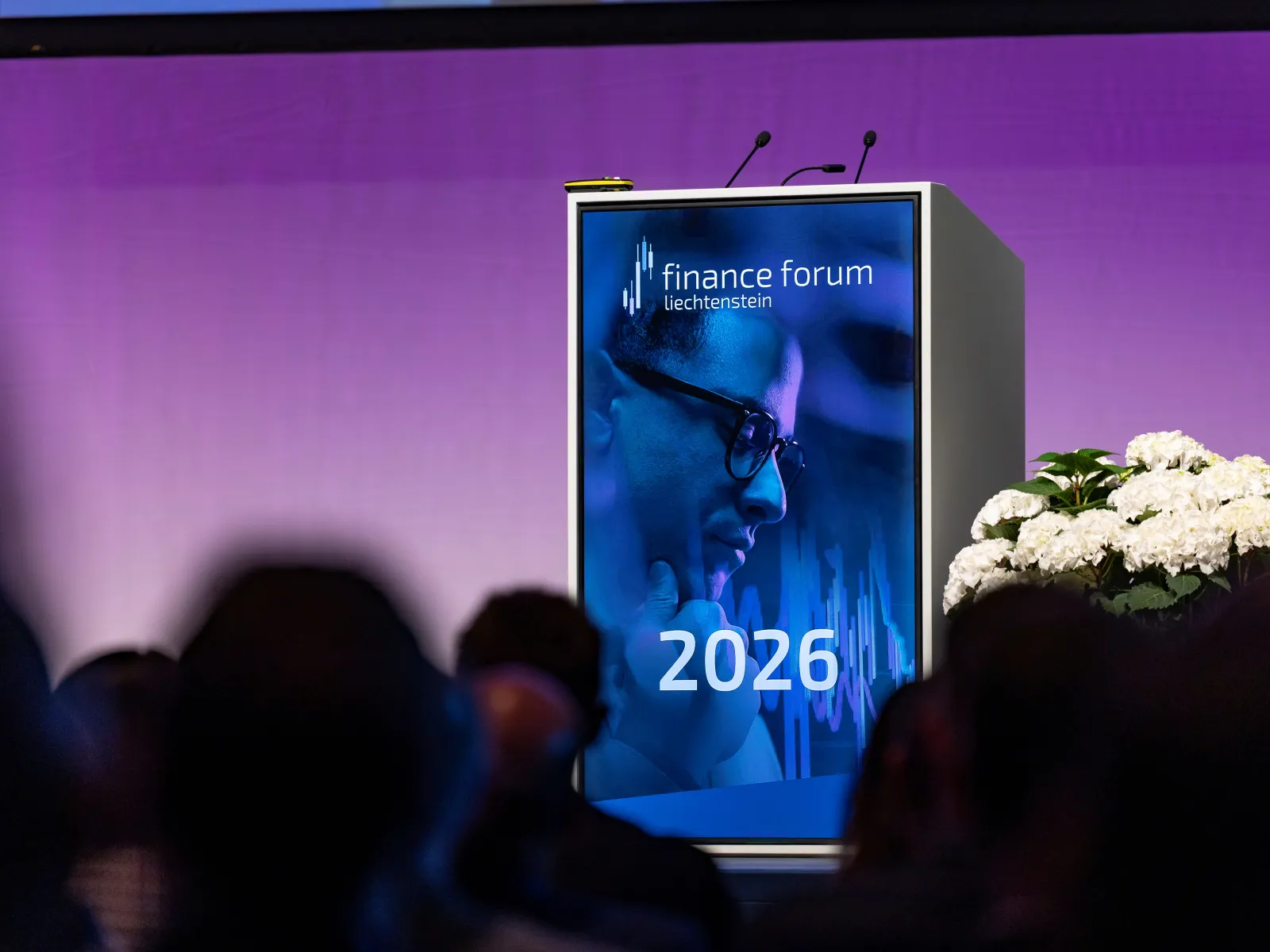 Finance Forum 2026 mit Veranstaltungsplakat und Gästen im Hintergrund