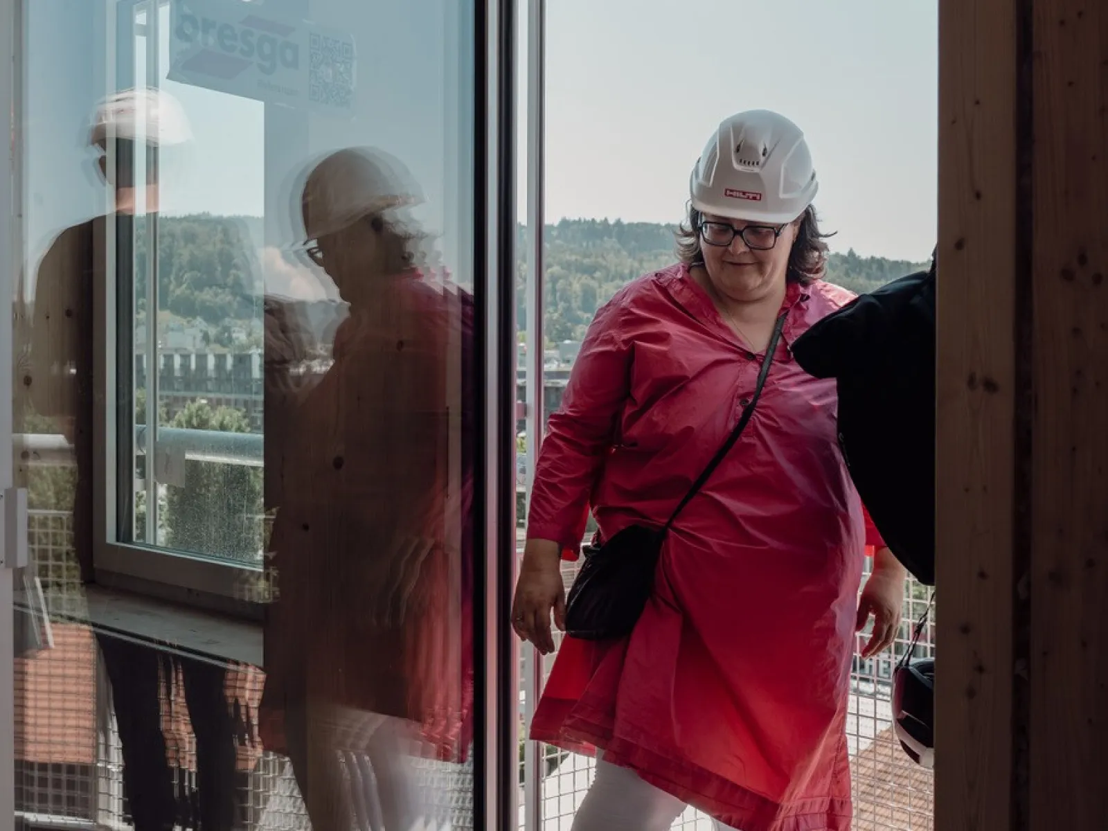 Eine Frau mit pinkem Kleid und einem weissen Bauhelm bei einer Baustellenbegehung 