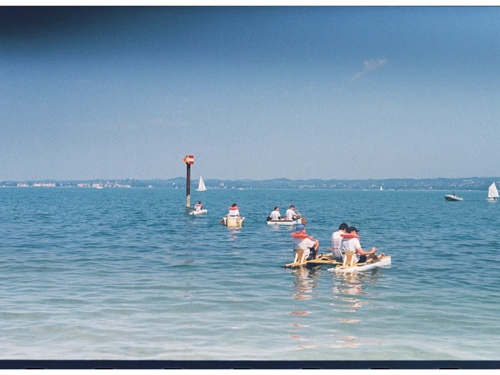 Mehrere Menschen mit selbstgebauten Booten in einem See. 