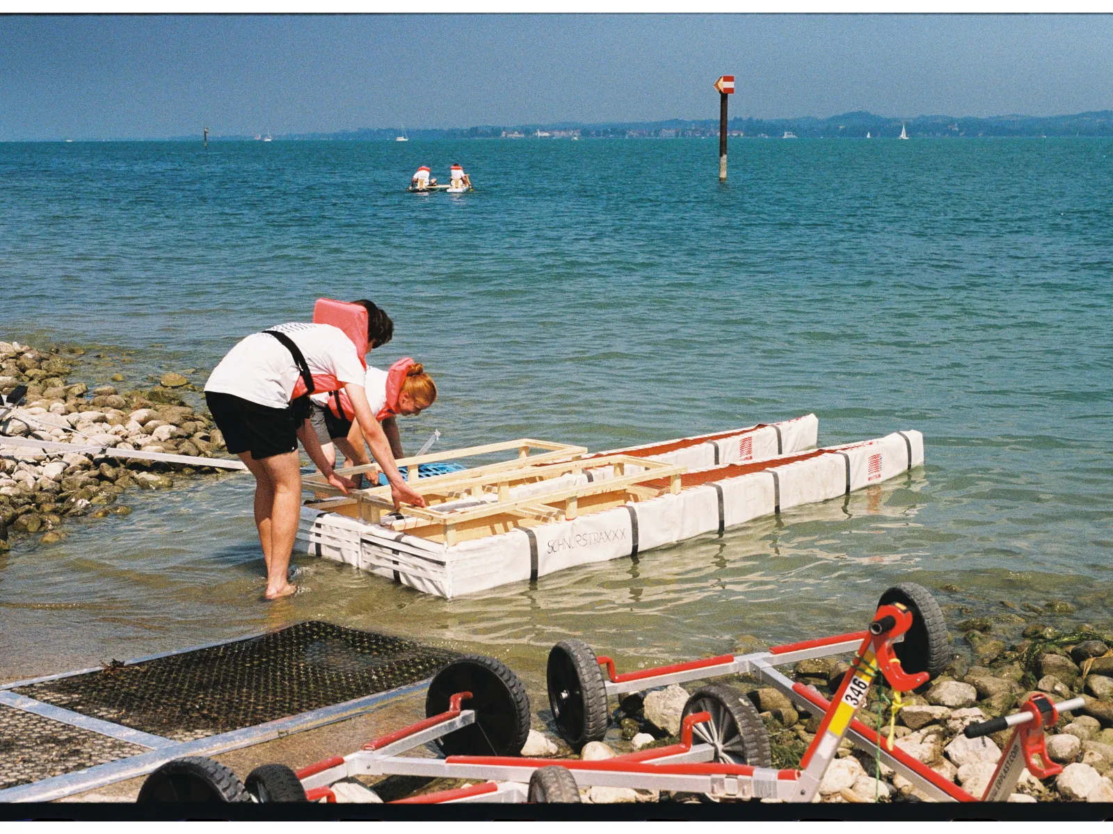 Zwei Personen lassen ein selbstgebautes Boot zu Wasser. 