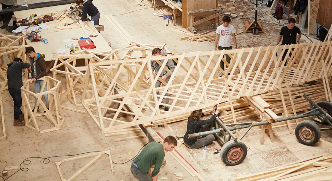Eine Holzwerkstatt wo ein Turm aus Holz von Menschen gebaut wird