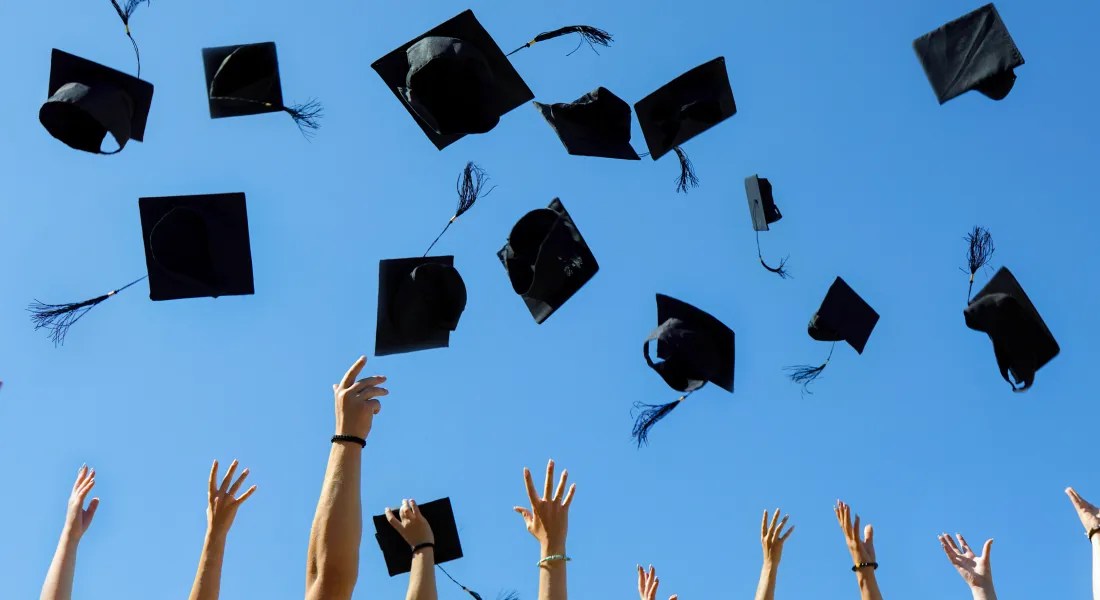 Studierende werfen Abschlusskappen in die Luft bei der Graduierungsfeier an der Universität Liechtenstein