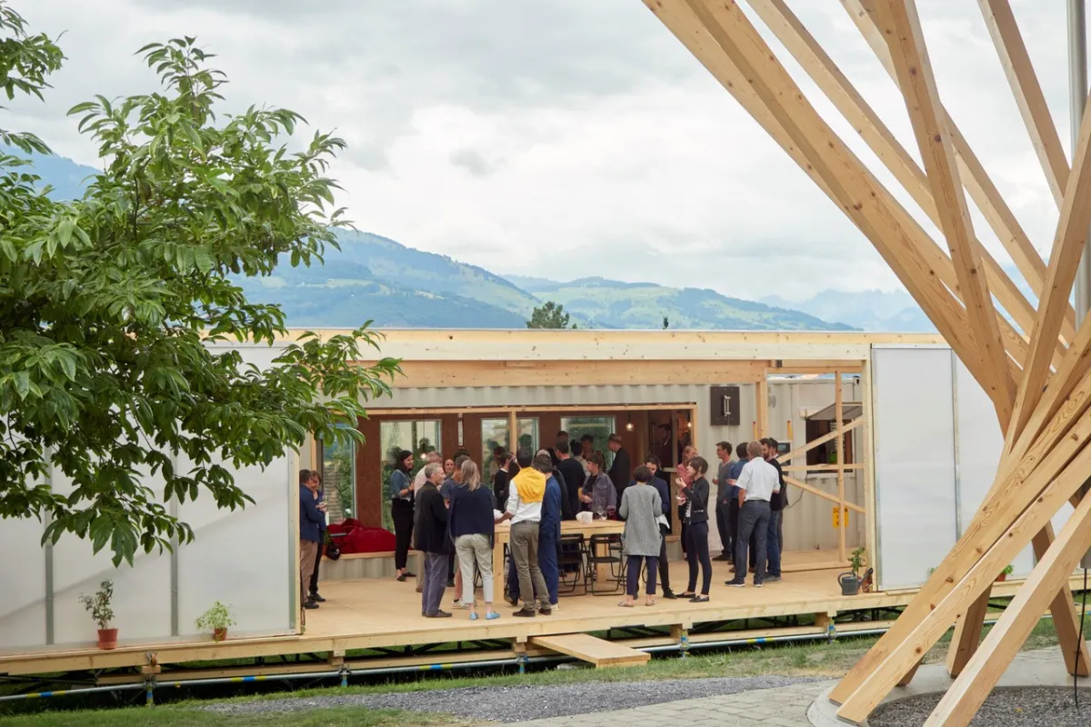 Aussenansicht des Base Camps, mit mehreren Menschen die davor stehen.