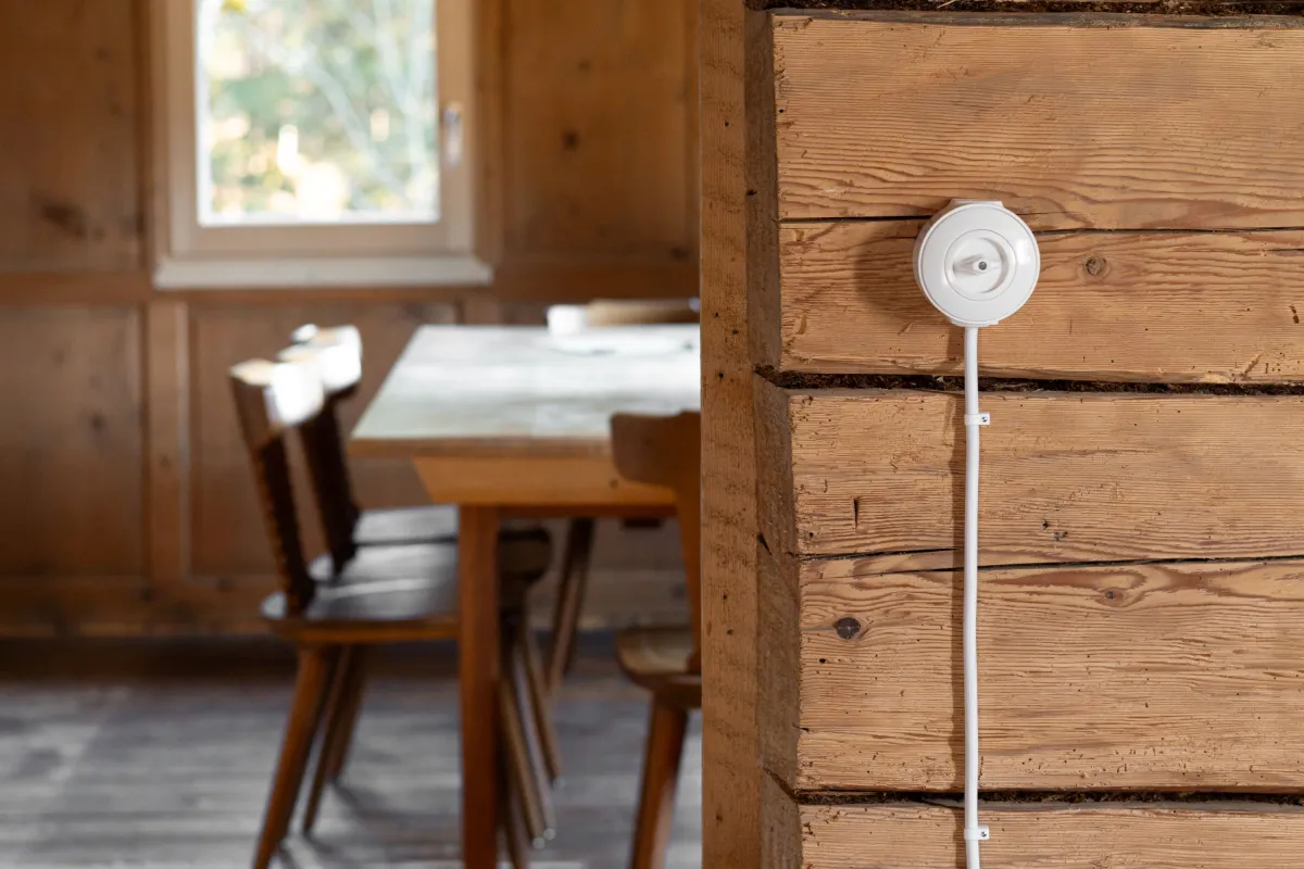 Ein weisser Lichtschalter an einer Altholzwand