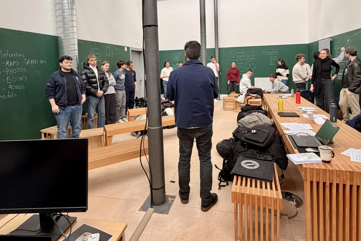 Mehrere Menschen stehen in einem grünen Raum mit Holzmöbeln
