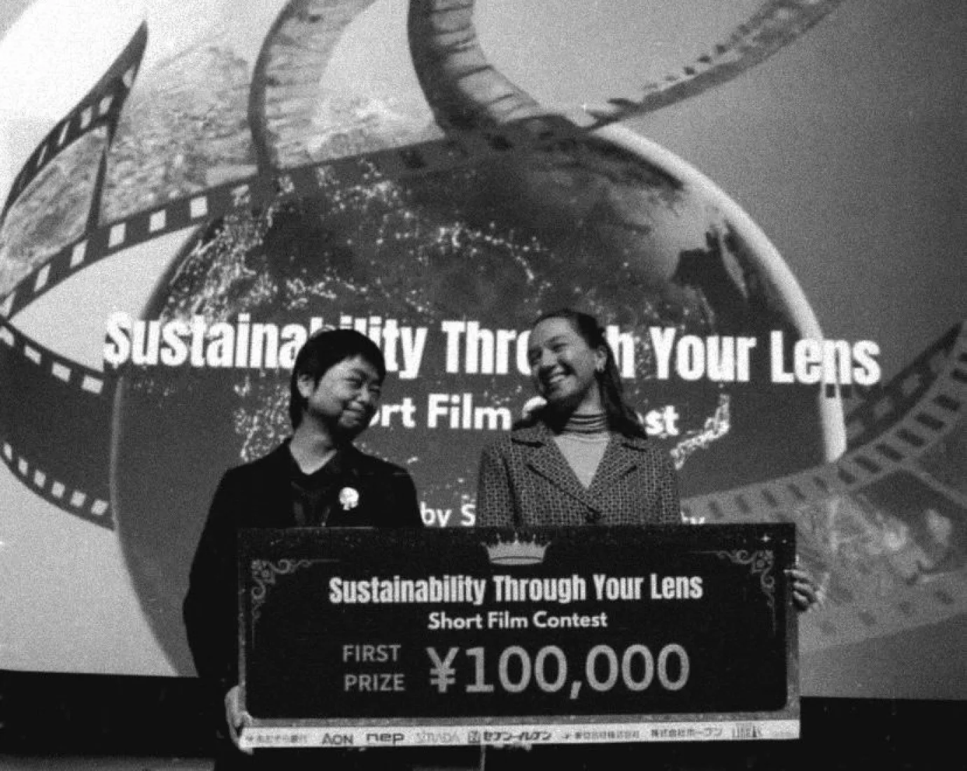 Schwarz-Weiss Aufnahme von zwei Frauen mit einem grossen Scheck in der Hand