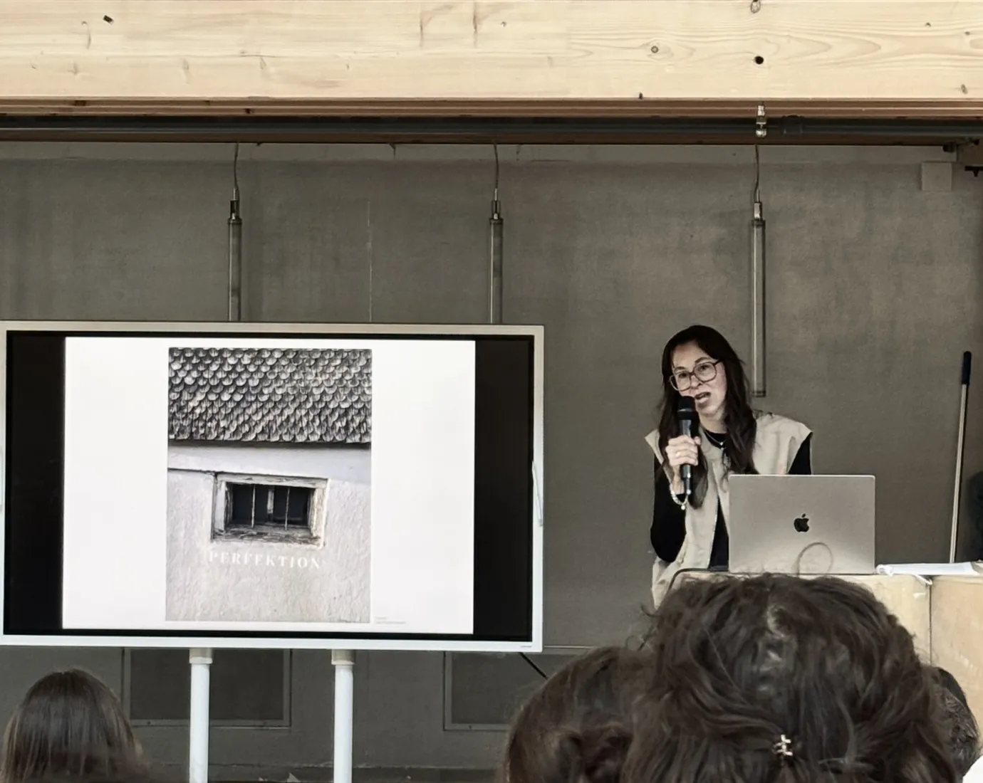 Vortragssituation mit einem Bildschirm und einer vortragenden Person