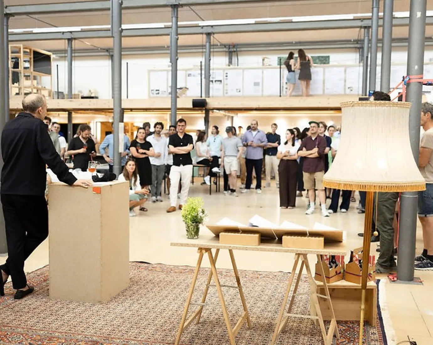 Publikum hört Mann mit Mikrofon in einem grossen Atelier zu 