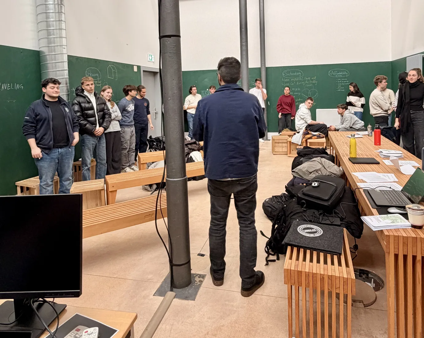 Mehrere Menschen stehen in einem grünen Raum mit Holzmöbeln