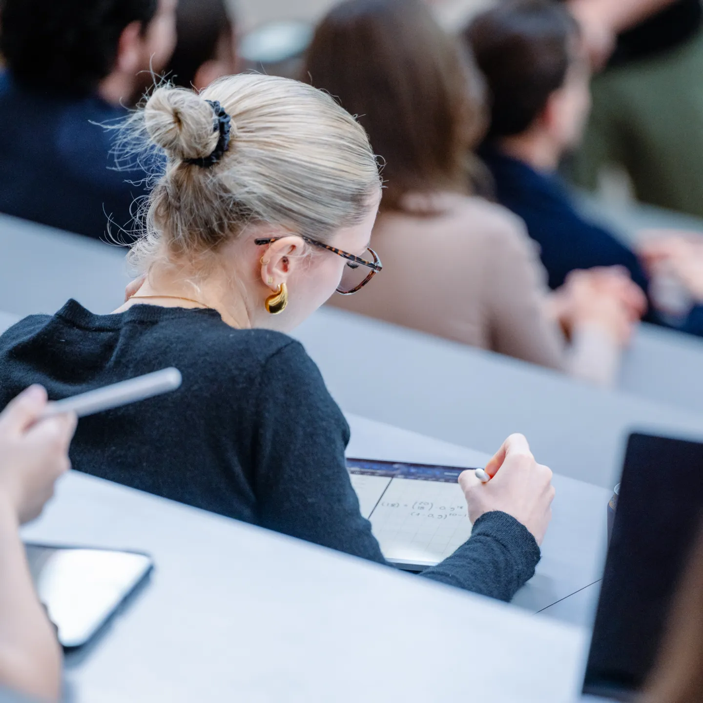 Eine Studentin macht sich digitale Notizen auf einem Tablet während einer Vorlesung an der Universität Liechtenstein.