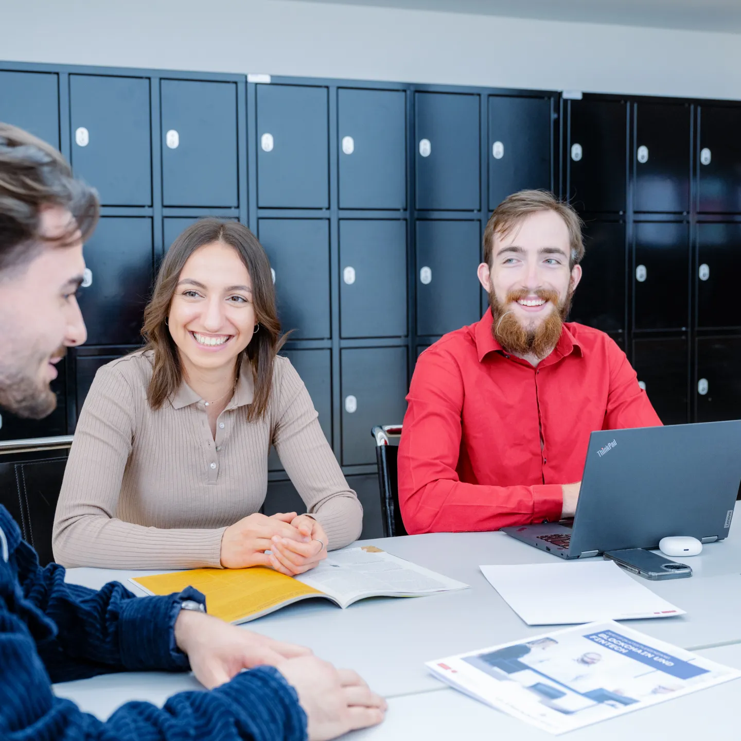 Studierende der Universität Liechtenstein arbeiten gemeinsam und lachen in entspannter Campus-Atmosphäre.