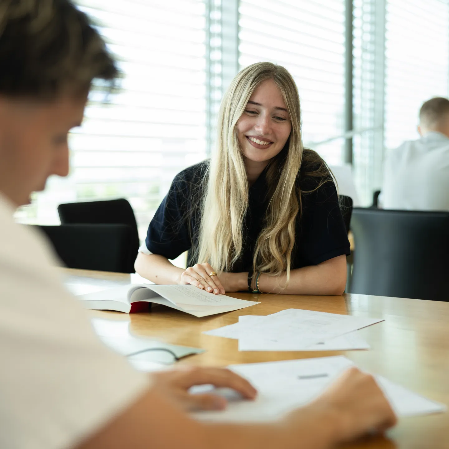 Studierende beim gemeinsamen Lernen in der Bibliothek der Universität Liechtenstein, Fokus auf Gruppenarbeit und Austausch.