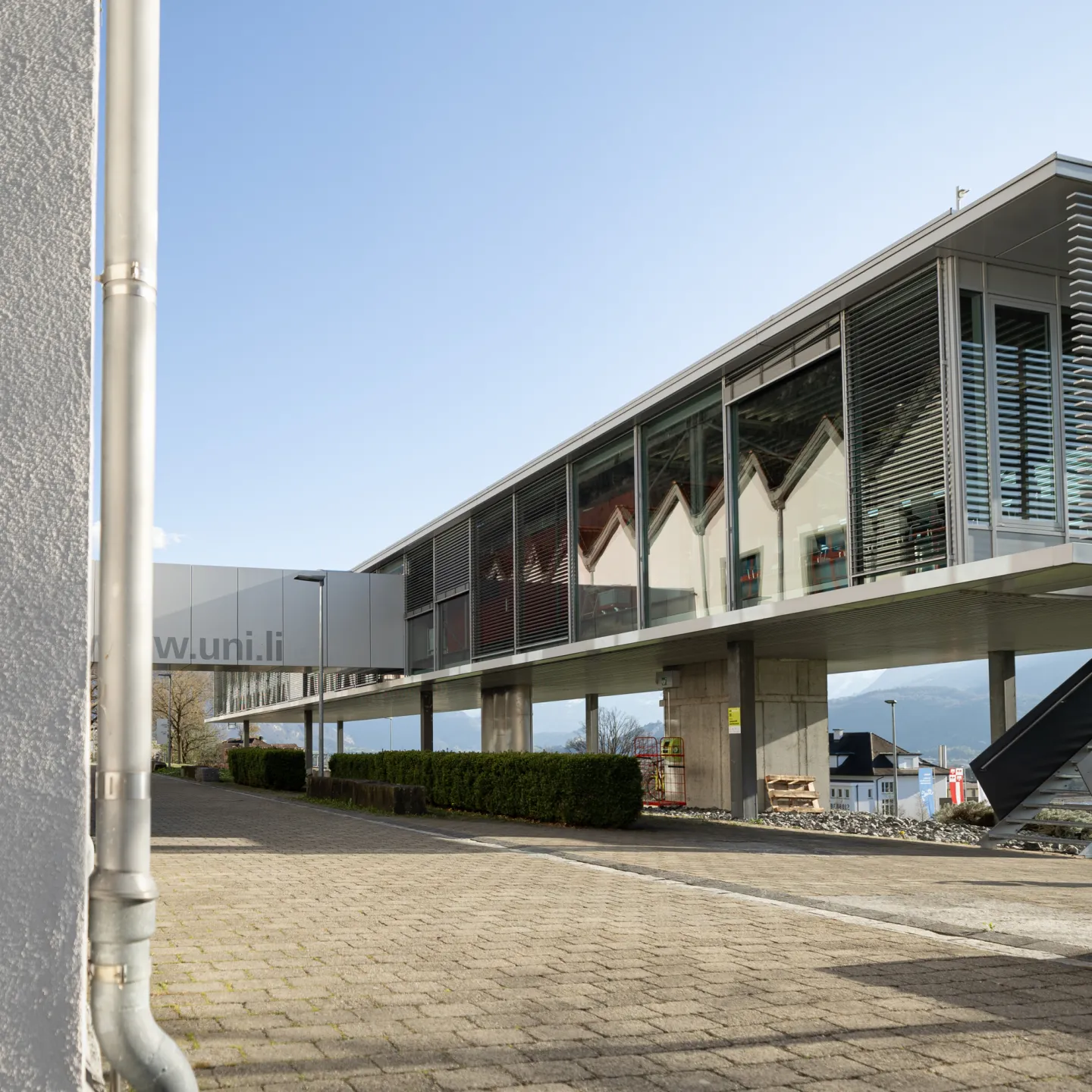 Moderne Architektur mit Glasfassade und Verbindungselementen auf dem Campus der Universität Liechtenstein.