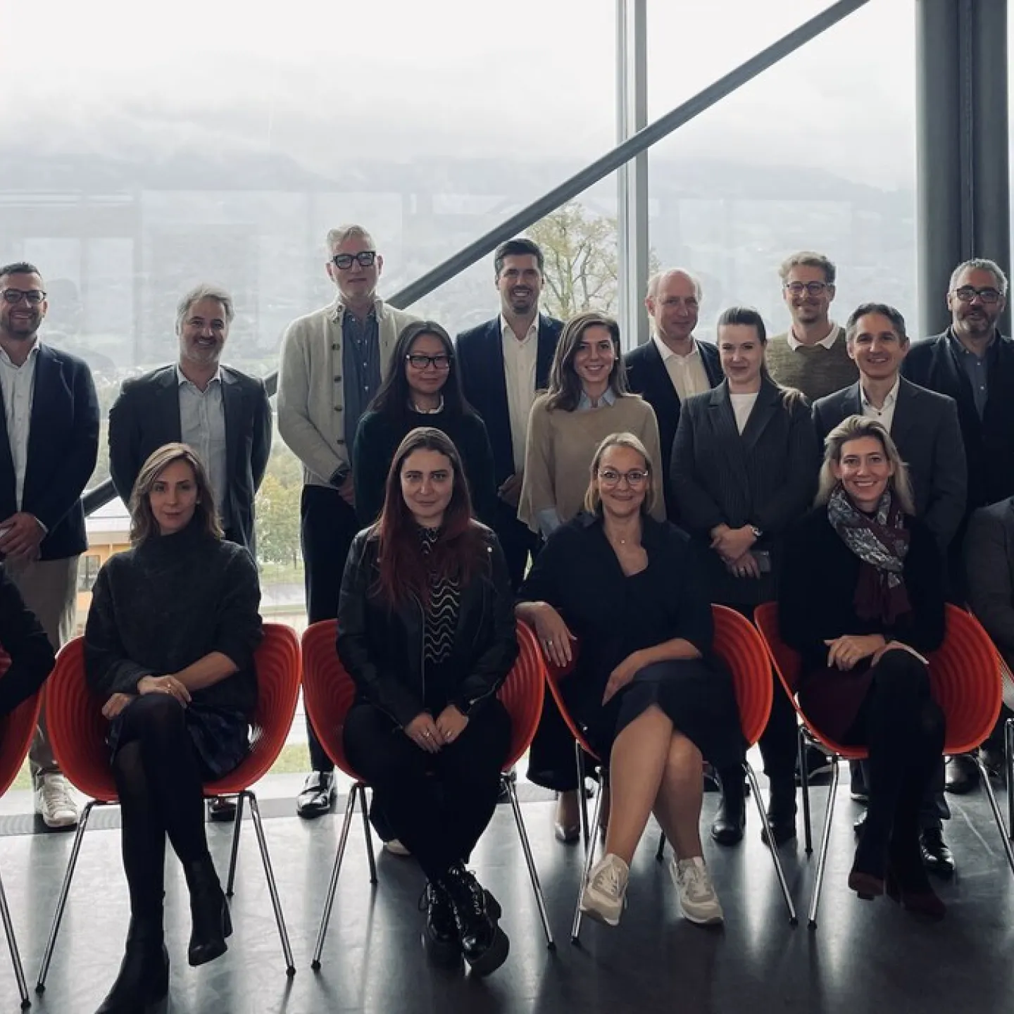 Gruppenfoto von Teilnehmenden der MiCAR Expert Roundtable Series an der Universität Liechtenstein. Die Personen stehen und sitzen in zwei Reihen vor einer großen Fensterfront mit Blick auf eine bergige Landschaft.