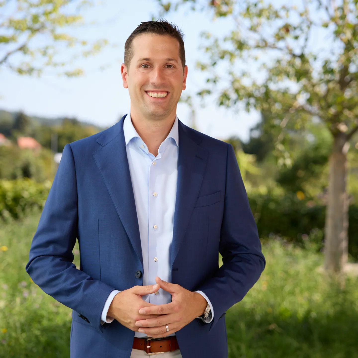 Porträt eines lächelnden Mannes im blauen Anzug im Freien an der Universität Liechtenstein.