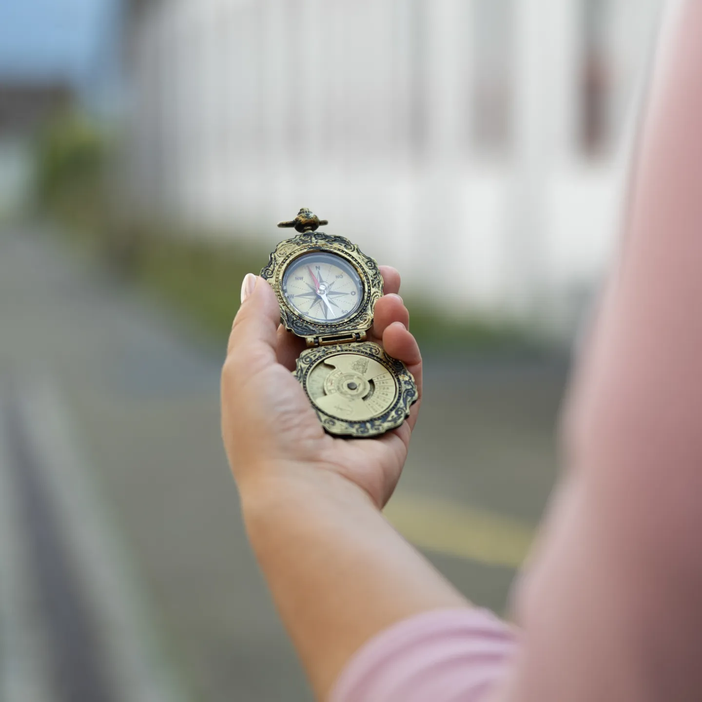 Hand hält antiken Kompass im Außenbereich der Universität Liechtenstein.
