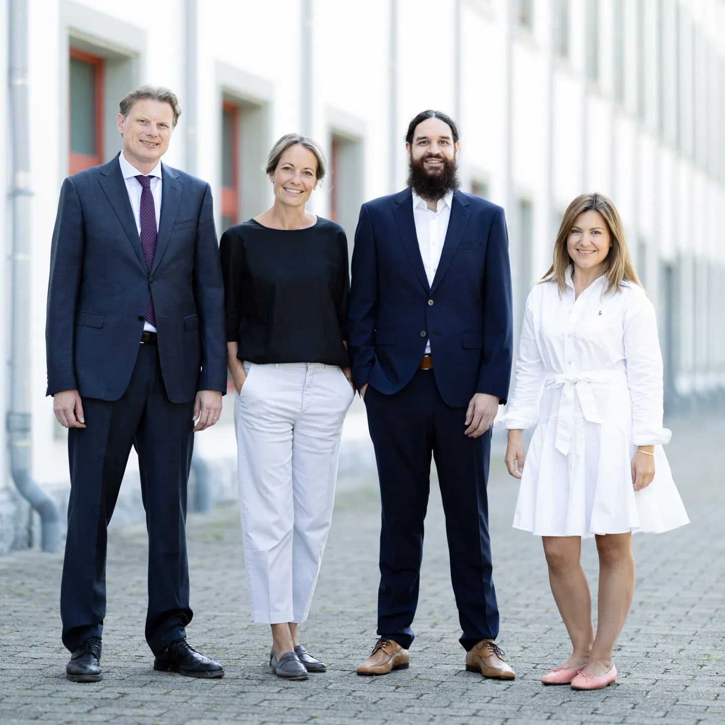 Vier Personen im Business Outfit vor dem Gebäude der Universität Liechtenstein.