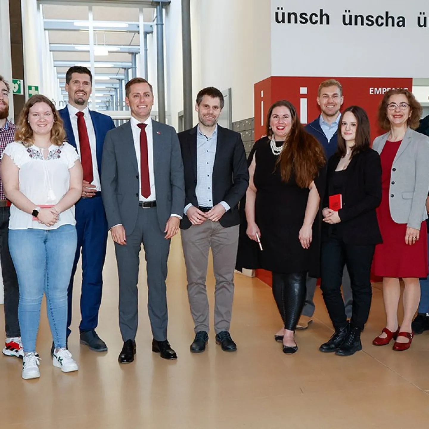 Gruppenfoto von Studierenden und Mitarbeitenden der Universität Liechtenstein mit US-Botschafter Scott C. Miller während seines Besuchs. Die Personen stehen in einem modernen Innenbereich der Universität.