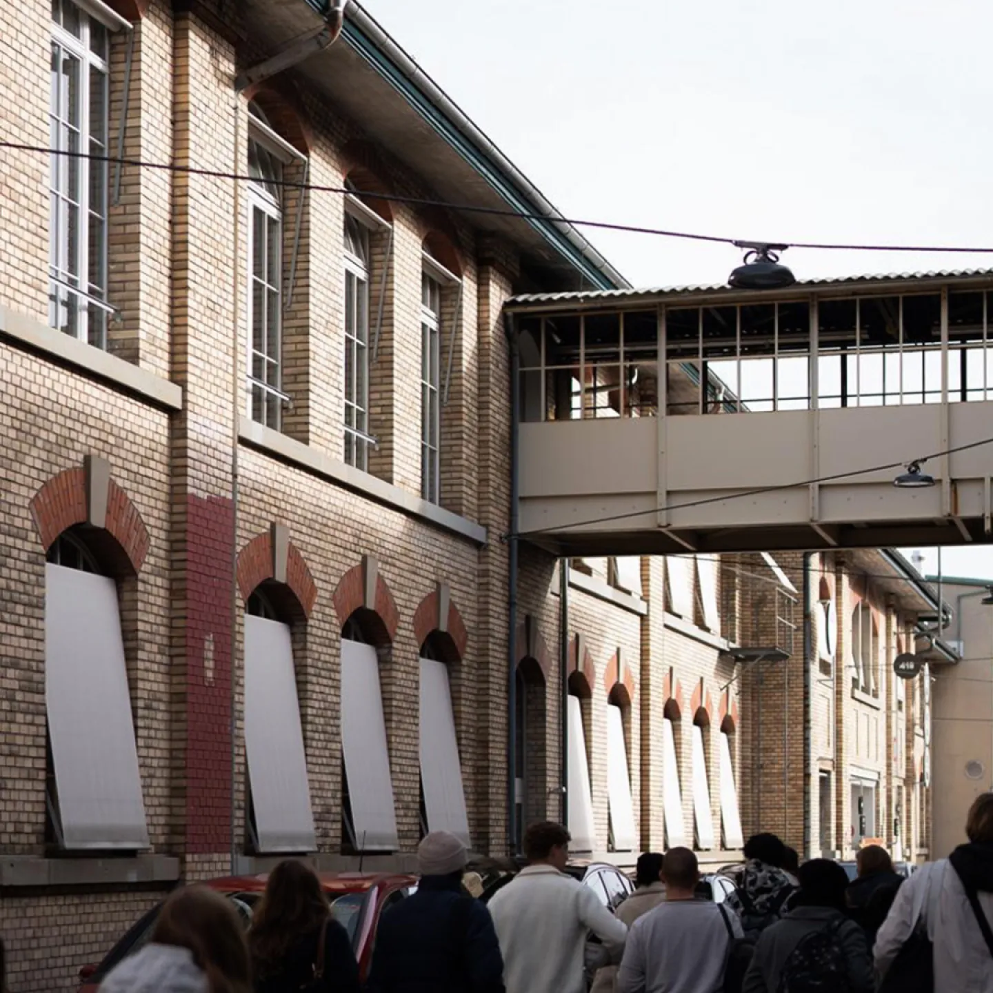 Mehrere Menschen laufen neben einem alten Fabriksgebäude