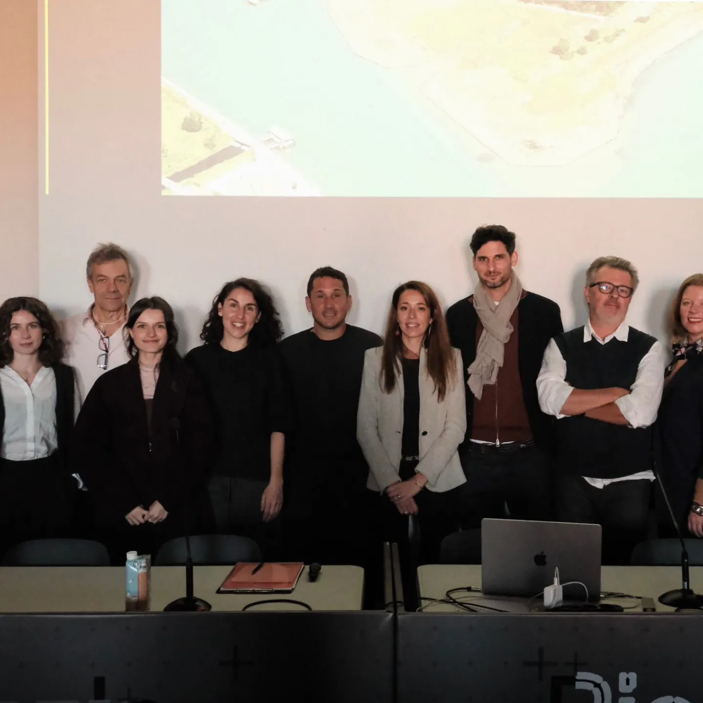 Ein Gruppenbild von 10 Personen vor einer Leinwand