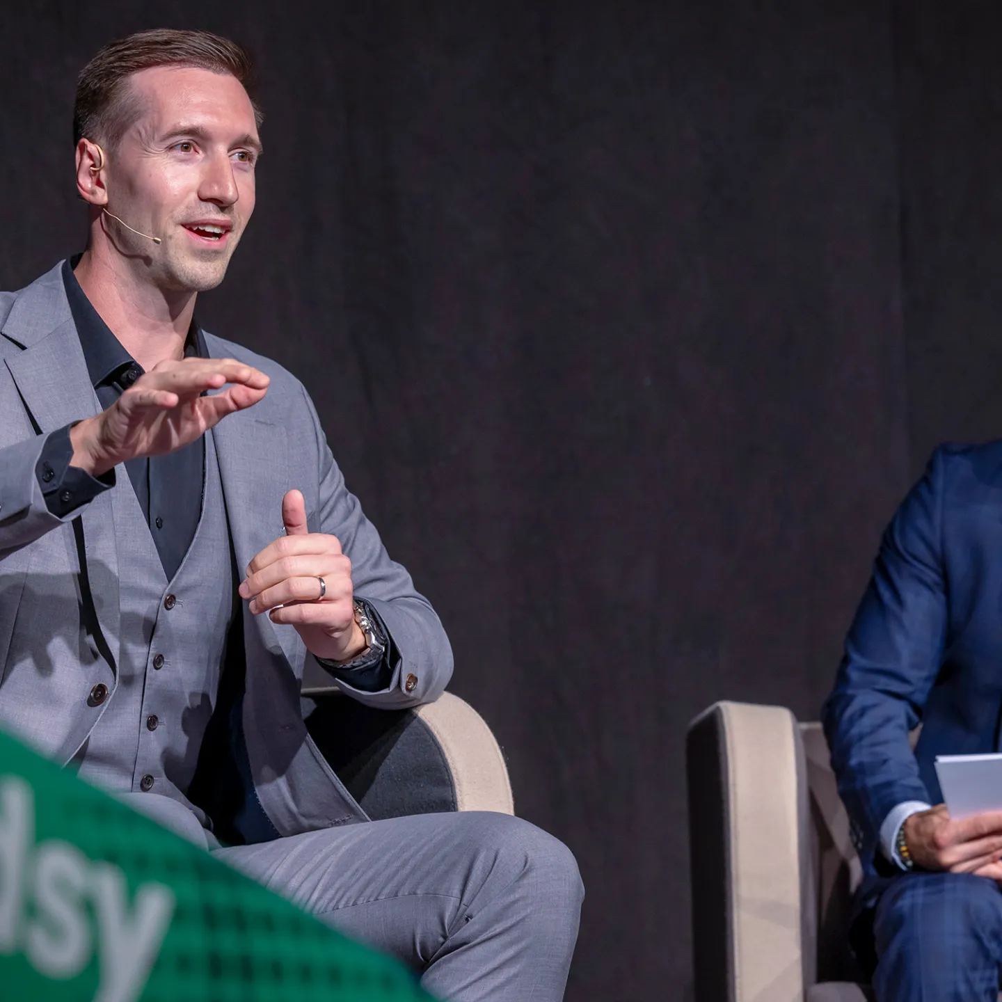 Referenten diskutieren auf Podium bei Wirtschaftskonferenz vor Publikum