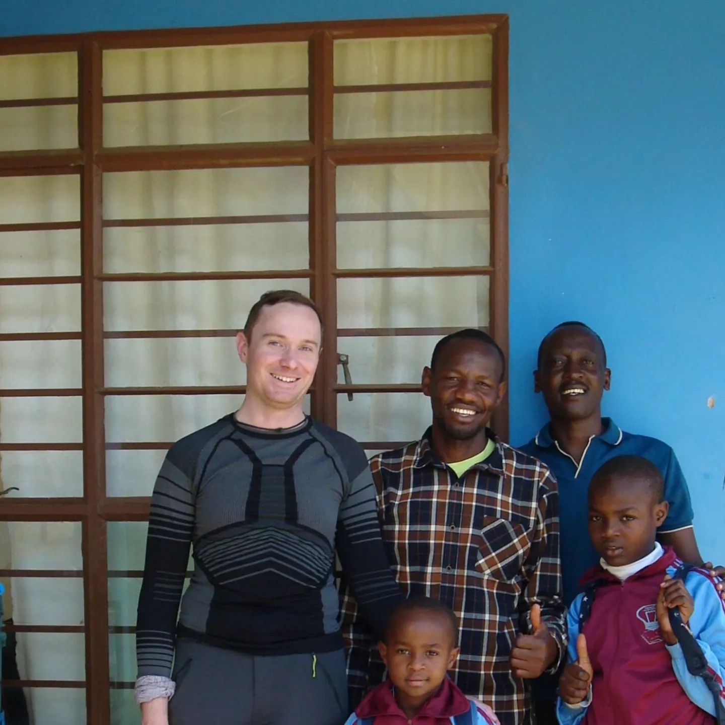 Gruppe von Personen steht vor einem blauen Gebäude.