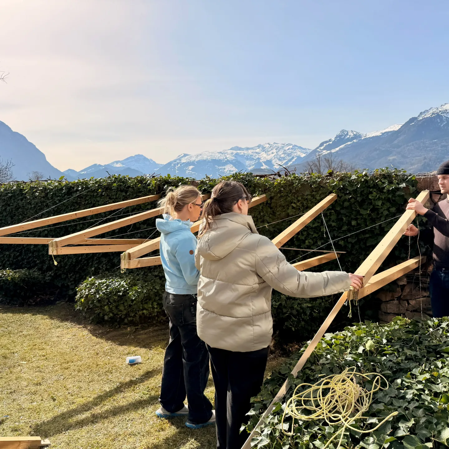 Drei junge Menschen bauen eine Konstruktion aus Holz 