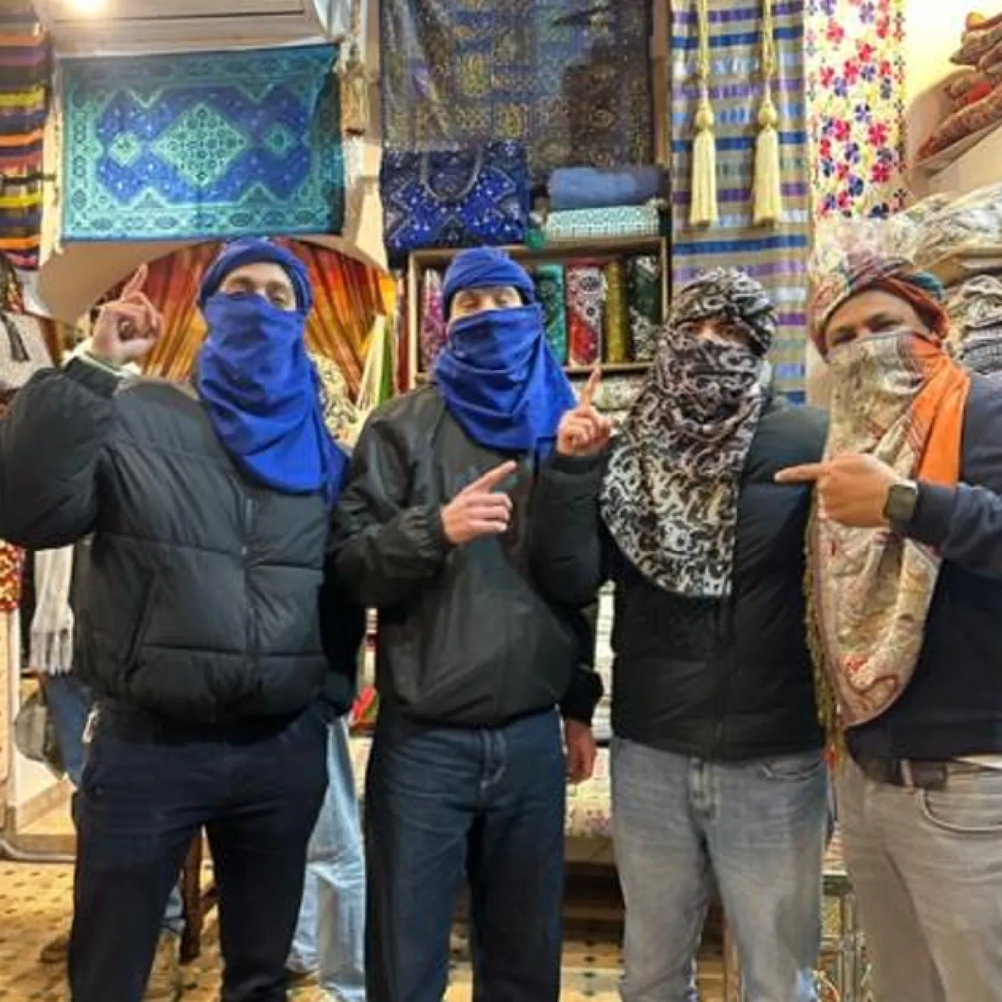 Vier Personen mit Tüchern im Laden vor bunten Stoffen.