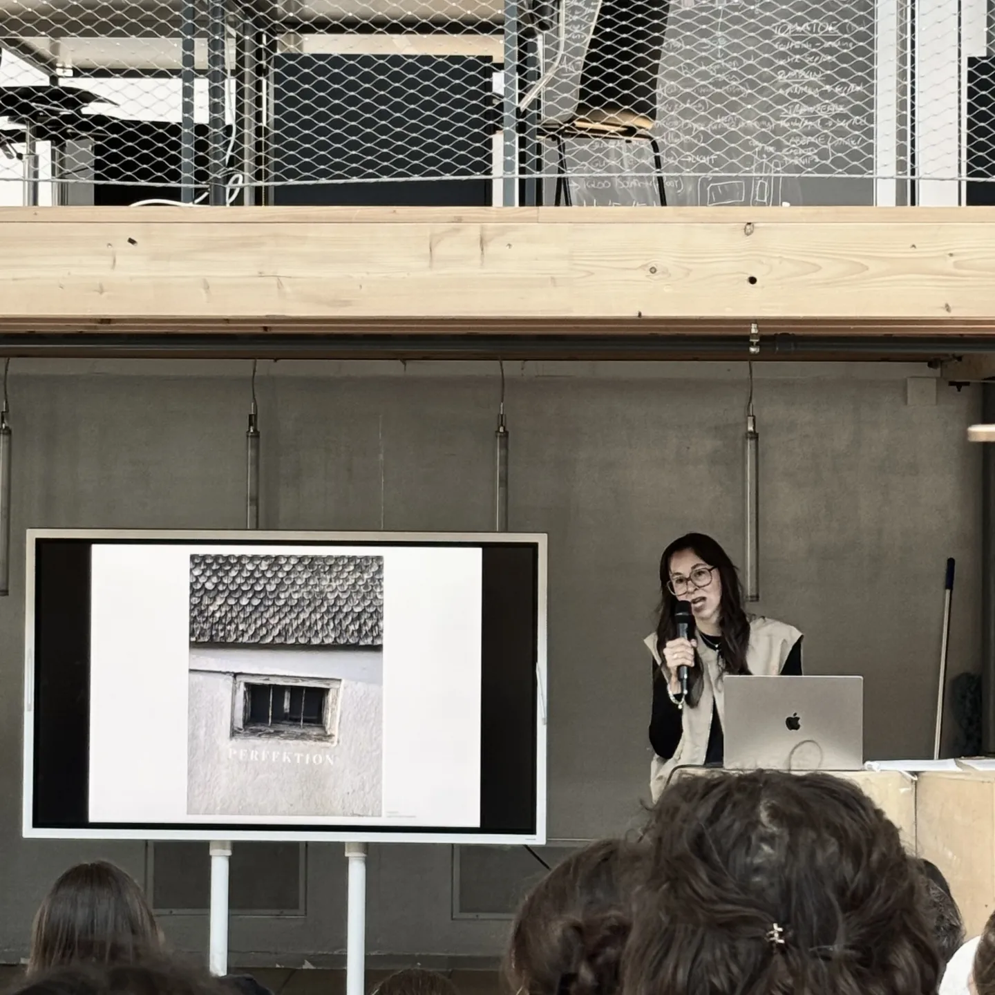 Vortragssituation mit einem Bildschirm und einer vortragenden Person