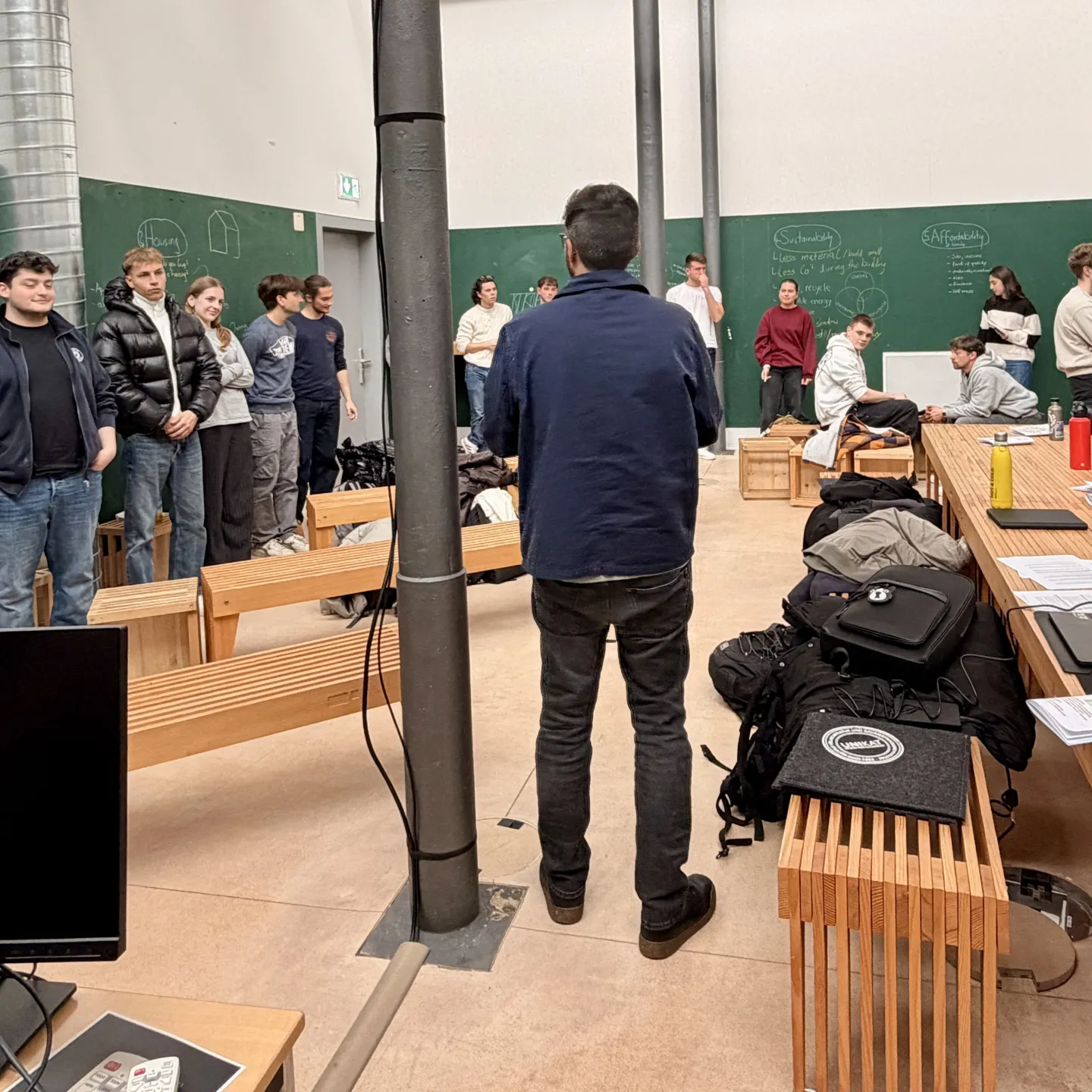 Mehrere Menschen stehen in einem grünen Raum mit Holzmöbeln