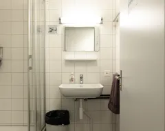 Badezimmer im Studierendenwohnheim der Universität Liechtenstein mit Waschbecken, Spiegel und Dusche.
