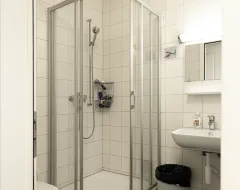 Badezimmer im Studierendenwohnheim der Universität Liechtenstein mit Dusche, Waschbecken und Toilette.