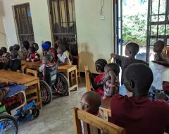 Kinder sitzen in einem Raum und schauen auf einen Fernseher.