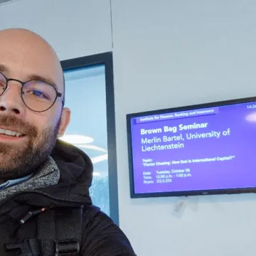 Mitarbeiter der Universität Liechtenstein vor Ankündigung eines Seminars zum Thema internationale Kapitalflüsse an der Wirtschaftsuniversität Wien.