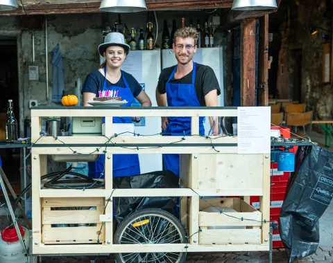 Zwei junge Menschen vor einer selbstgebauten Bar aus Holz