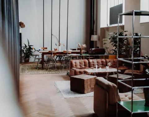 Gemütlicher Raum mit Sofas, Pflanzen und einem großen Tisch, ideal für Treffen und Networking-Veranstaltungen.